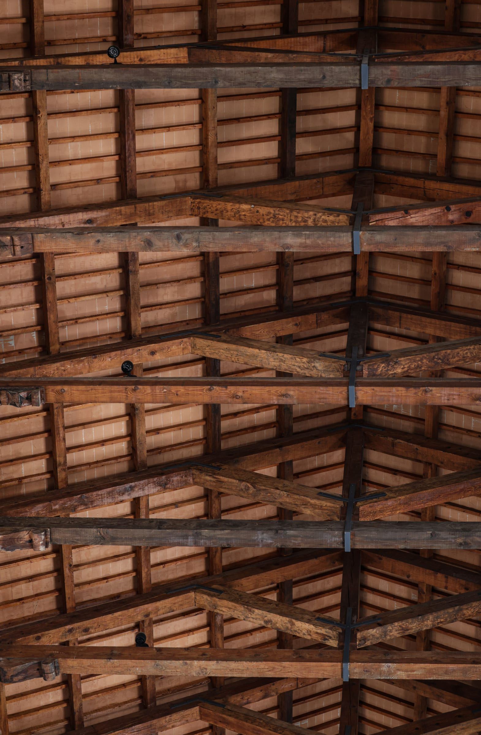 Alter Dachstuhl aus dunklem Holz, von unten gesehen