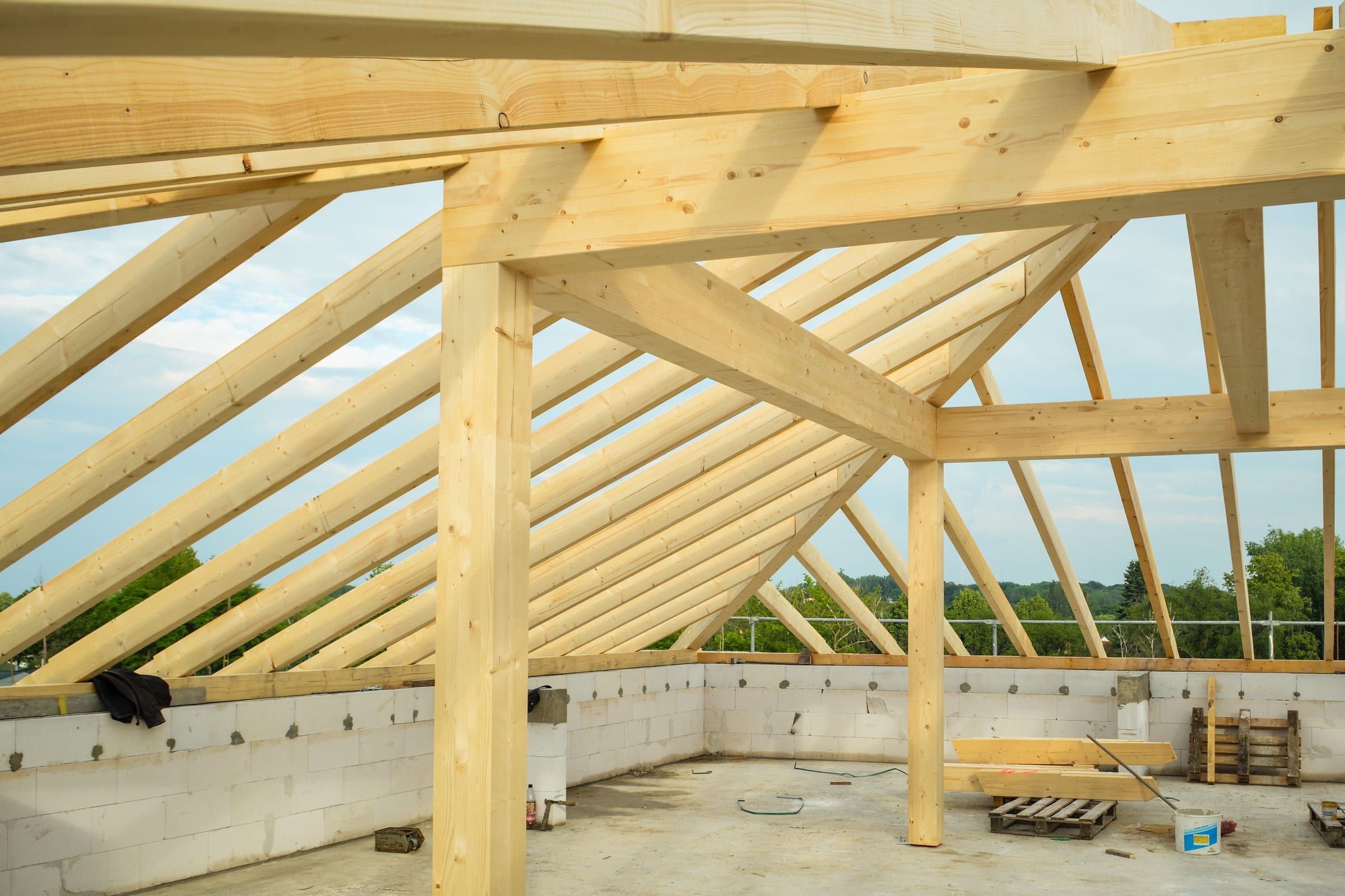 Neuer Dachstuhl aus hellem Holz auf einem gemauerten Rohbau